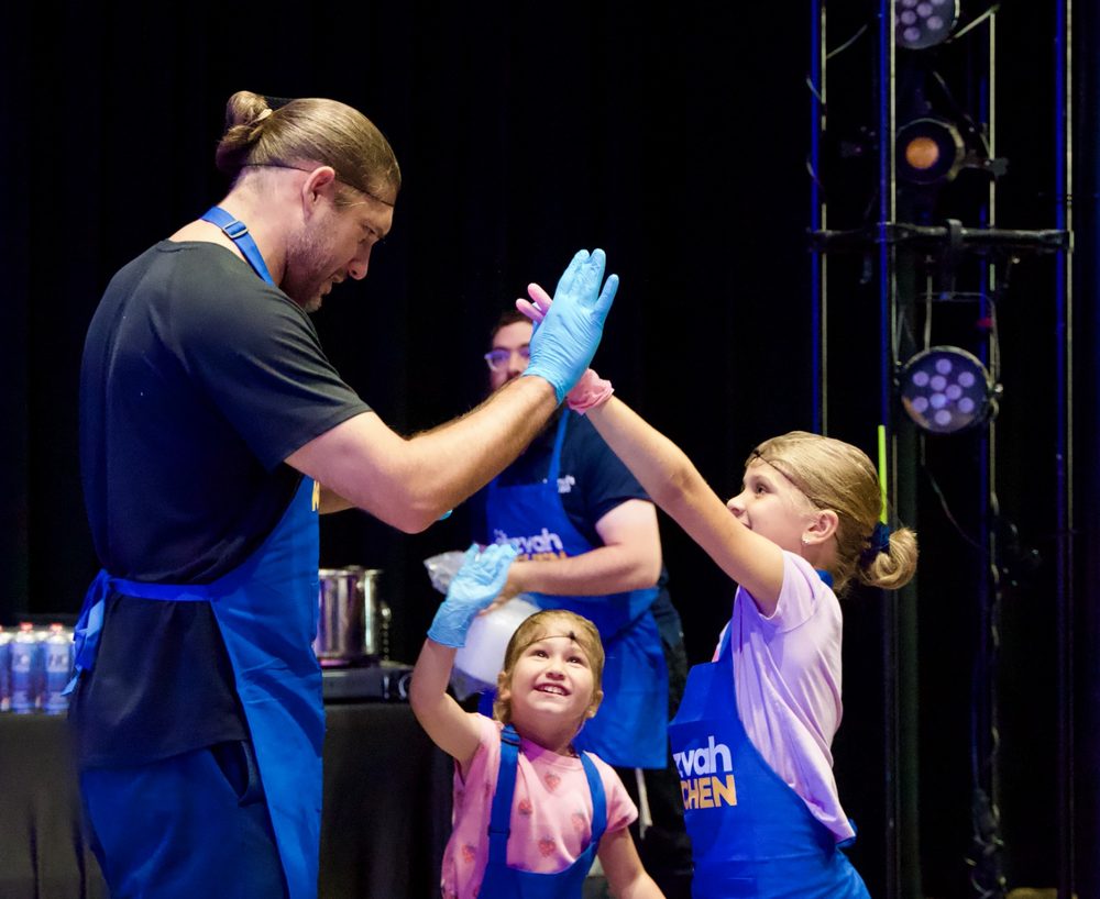 Kids and volunteers high-fiving at Mitzvah Kitchen